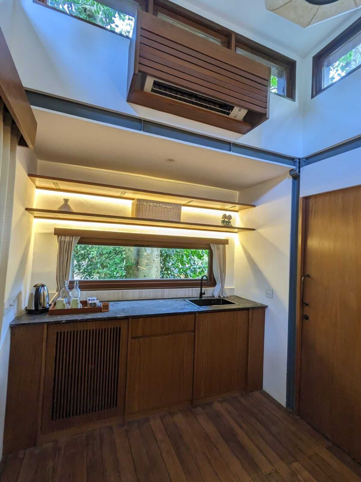 Een kleine keuken met raam, inbouwventilatie en een houten deur.