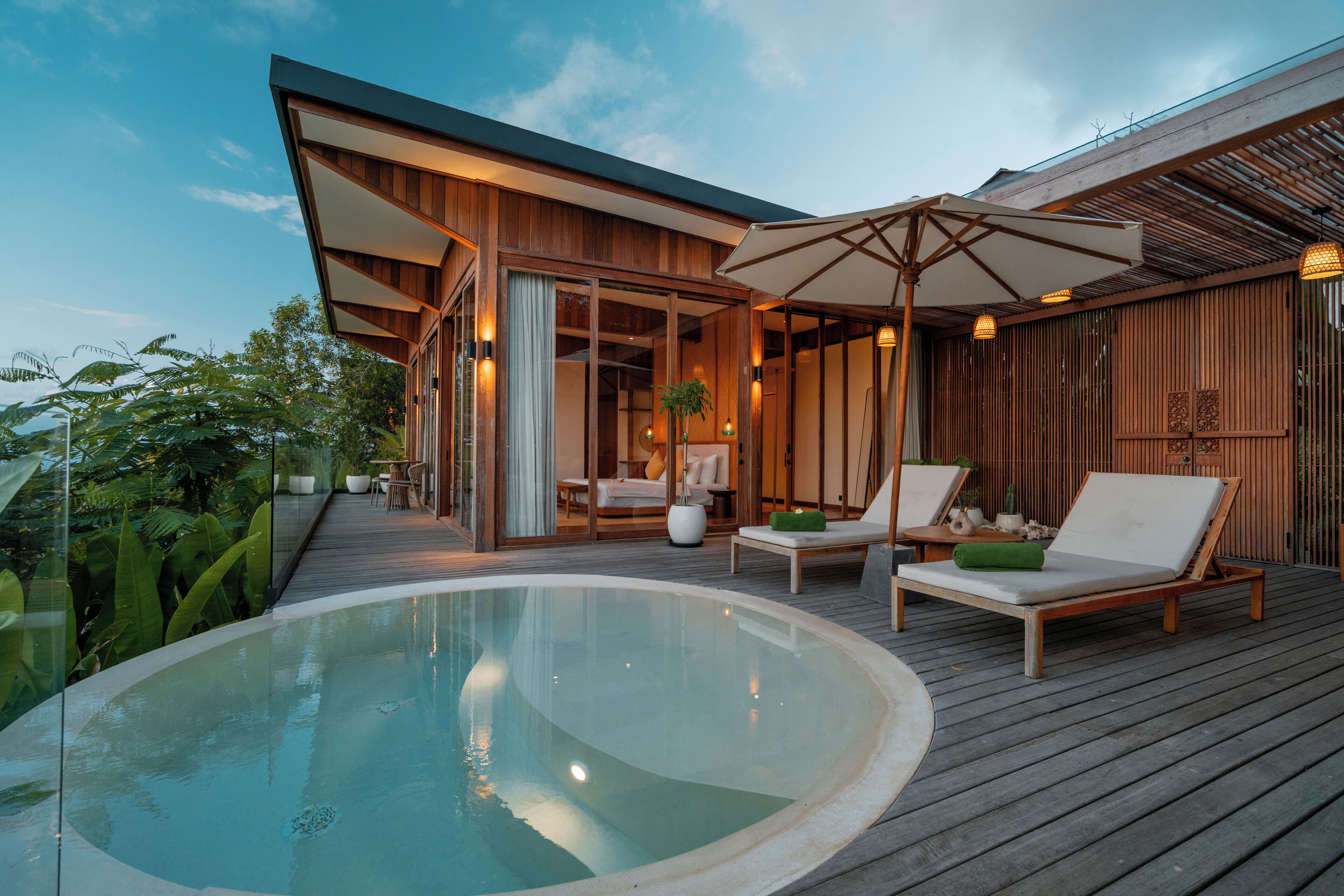 Un espace piscine extérieur moderne, doté de chaises longues et d’une terrasse en bois.