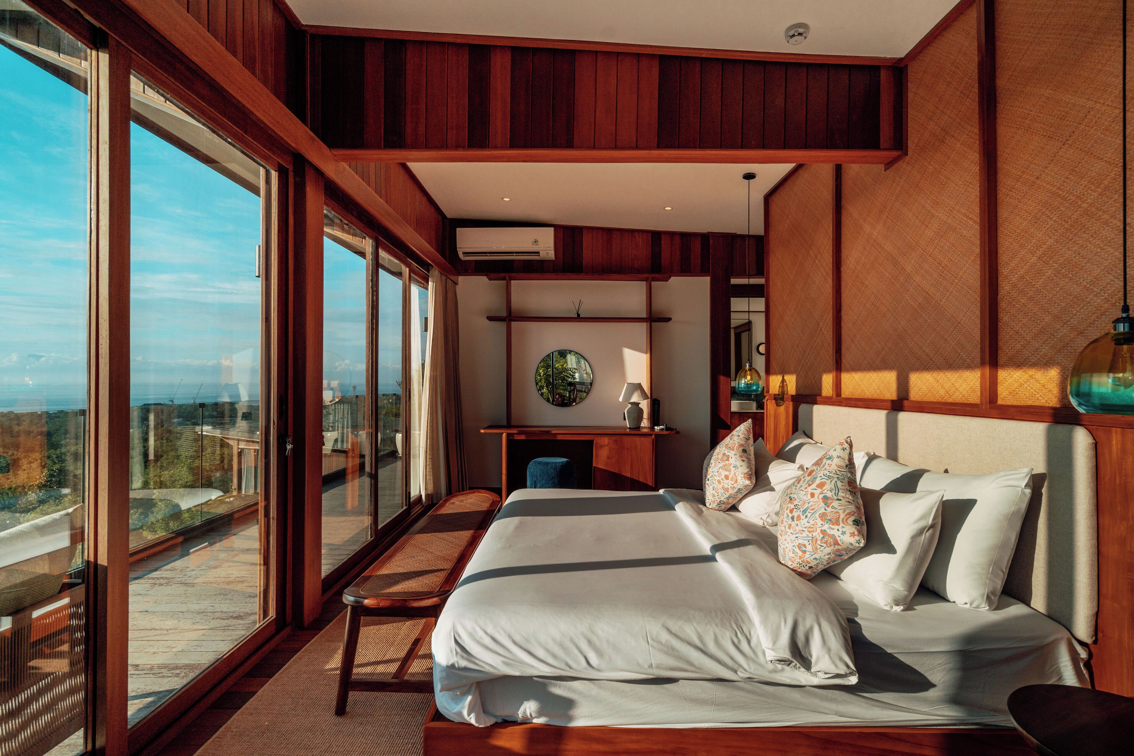 A modern hotel room with a large bed, a desk, and a view of the city.