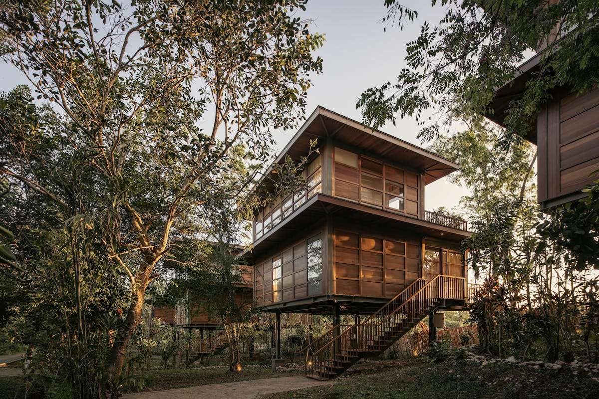 A two-story wooden house with a balcony and a staircase leading to the upper level.