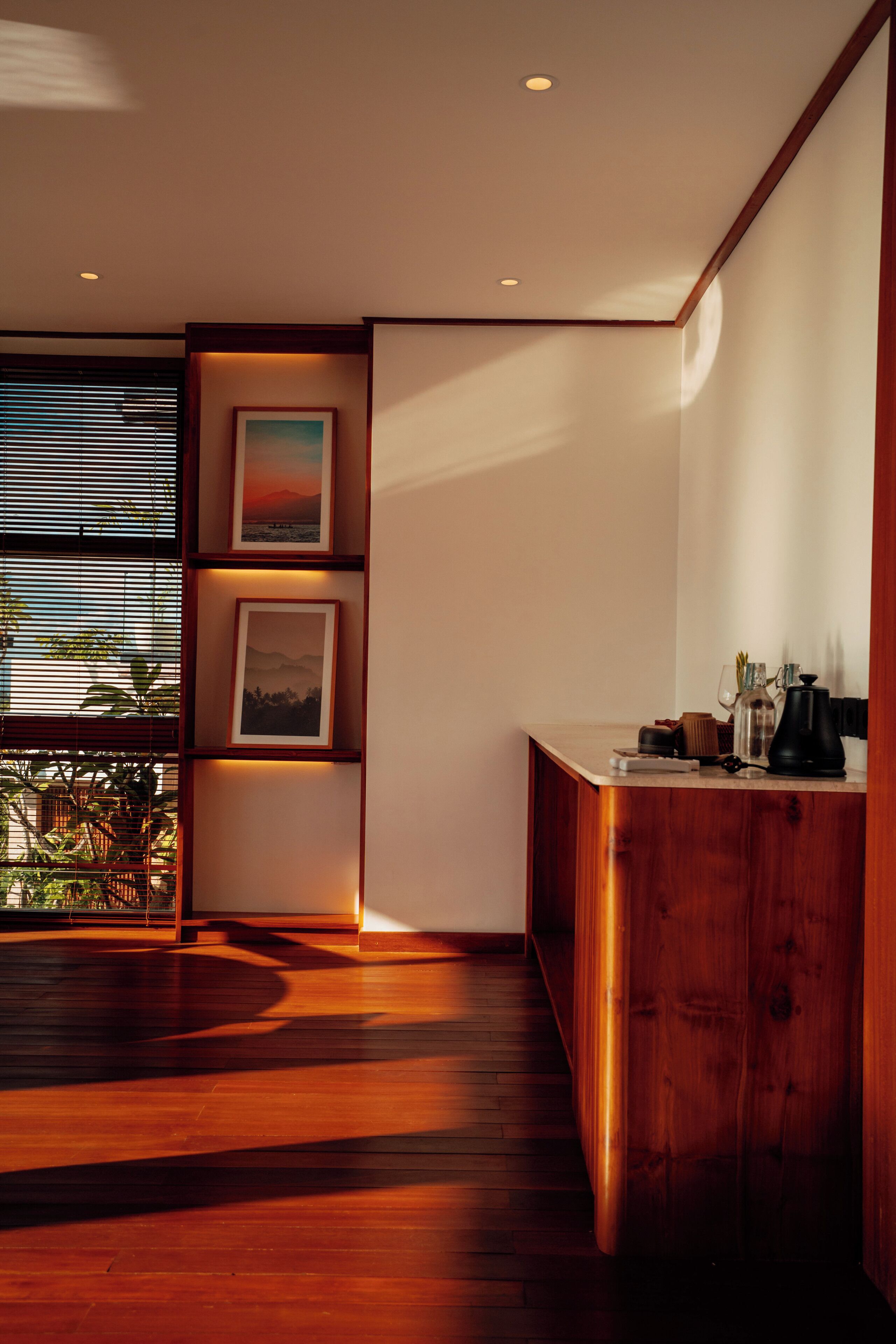 Ein modernes Interieur mit Holzboden, einer Holzkommode und gerahmten Bildern an der Wand.