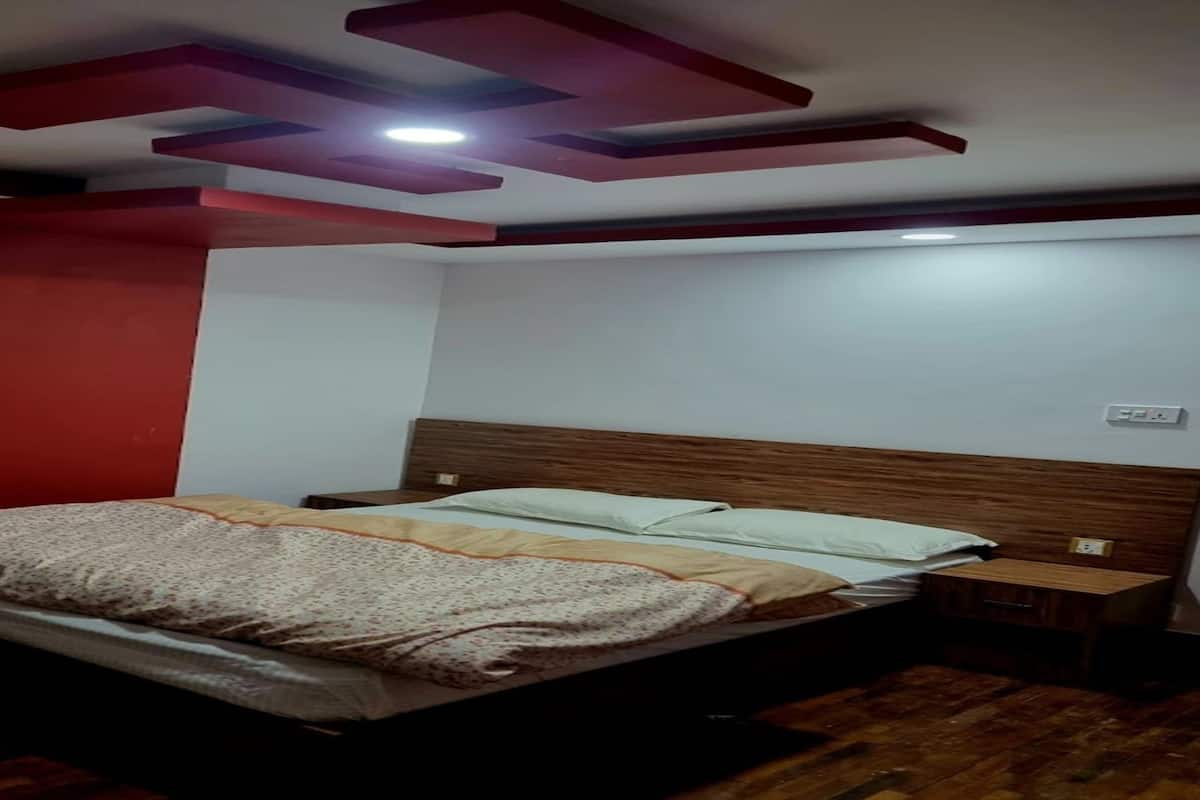 Un dormitorio con una cama de madera, una pared de acento roja y un diseño moderno en el techo.