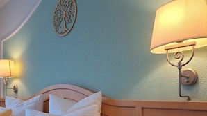Habitación de hotel con cama, lámparas de noche, teléfono y un adorno en la pared.