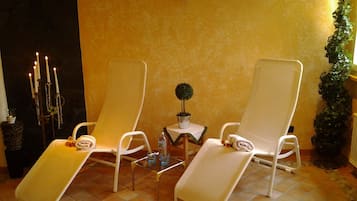 Relax in this inviting space with two lounge chairs and a candelabra, surrounded by a subtle patterned wall and terracotta floor.