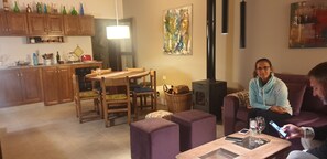 Ein gemütliches Wohnzimmer mit Essbereich, Kamin und einer Küche im Hintergrund.