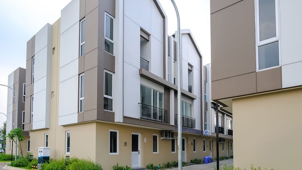 Un moderno edificio residencial de varios pisos, con balcones, techo plano y un diseño contemporáneo y limpio.