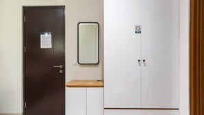 Una habitación con una puerta de madera oscura, un armario blanco con un espejo encima y una pequeña mesa de madera.