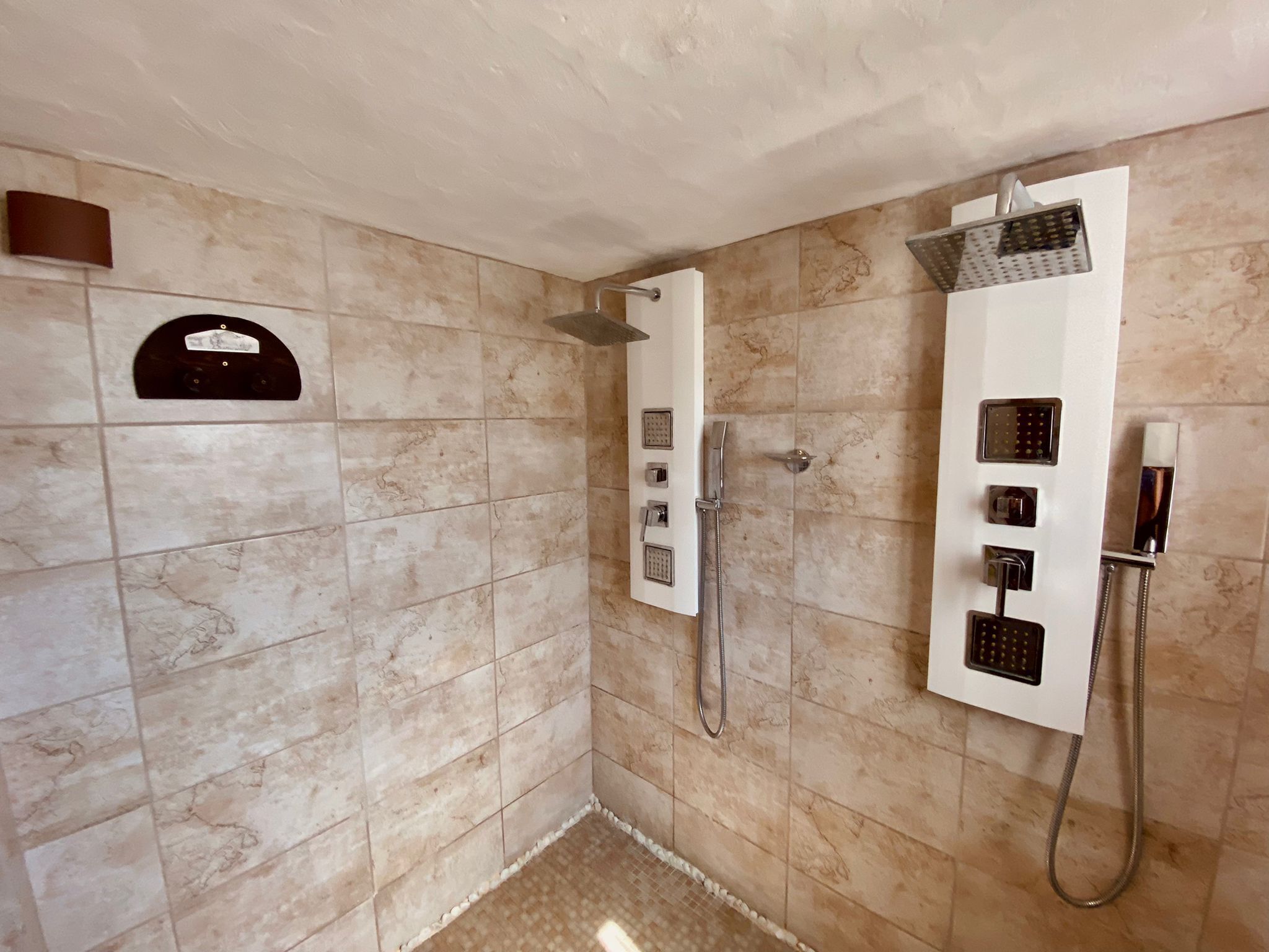 Un baño moderno con cabina de ducha a ras de suelo, ducha de mano y panel de control empotrado.