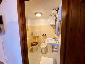Un baño con inodoro, bidé, lavamanos y una toalla en el suelo.