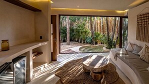 A modern interior with a large window, a wooden table, a sofa, and a built-in kitchen area. - Taio Tulum (Tulum)