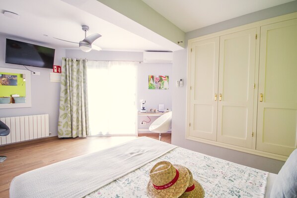 A hotel room with a bed, a desk, a chair, a wardrobe, a television, and a window with curtains. - Room with a breathtaking view over the mountains to the Mediterranean Sea (VC)