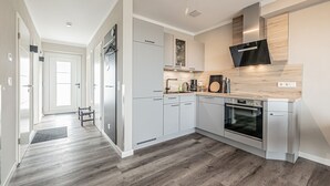 A modern kitchen with grey cabinets, a stainless steel refrigerator, a built-in oven, and a microwave. - Vacation home behind the dike for 6 pers. (Büsum)