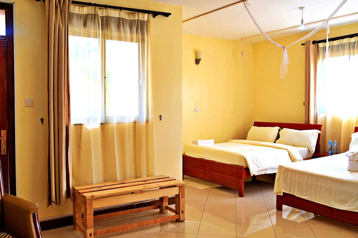 A hotel room with a wooden bed, a bench, a desk, and a chair.