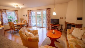 Een woonkamer met een bank, fauteuil, eettafel en televisie.