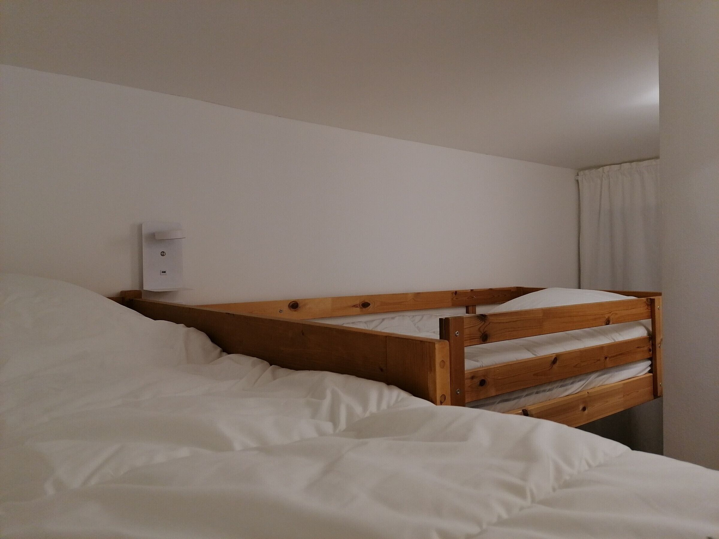 Ein Stockbett mit Holzrahmen und weißer Bettwäsche.