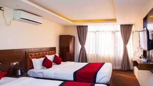 A hotel room with two beds, a television, an air conditioning unit, and a minibar. - MeroStay004 (Kathmandu)