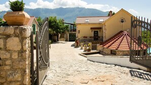 A stone pathway leading to a building with a tiled roof and a gate.