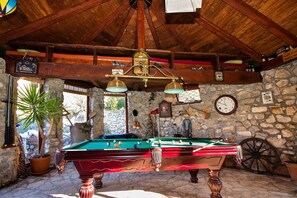 A billiards room with two pool tables, wooden beams, stone walls, a clock, and various memorabilia. - Five Bedroom Holiday Home With Pool and Sauna (Zadvarje)