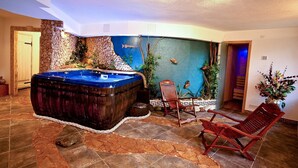 A spa area with a hot tub, wooden chairs, and a decorative wall.
