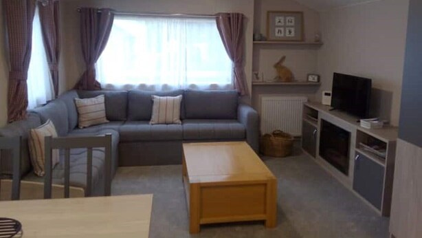 A living room with a sofa, a wooden coffee table, a television, and a radiator. - Peaceful "Coorie-in" Boat of Garten (Boat of Garten)