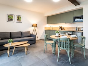 A modern living room with a sofa, coffee table, and dining area with chairs and a table set for two.