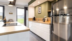 Une cuisine moderne dotée d’un réfrigérateur en acier inoxydable, d’un plan de travail en bois et de meubles blancs.