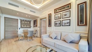 A modern living room with a white sofa, a glass coffee table, and a dining area with a table and chairs. - Elegant 1 Bed l Dubai Marina l City Skyline View I Studio One Tower (Dubai Marina)
