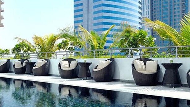 A rooftop pool area with lounge chairs and a clear view of tall buildings in the background. - Elegant 1 Bed Escape | Walk to Metro Station | JLT (Jumeirah Lake Towers)