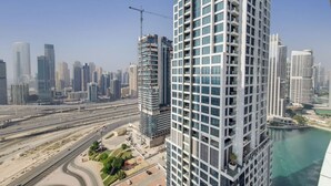 A high-rise building with a modern design, surrounded by other tall buildings and a highway. - Elegant 1 Bed Escape | Walk to Metro Station | JLT (Jumeirah Lake Towers)