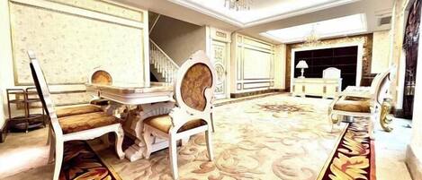 Una habitación lujosa con una imponente araña, muebles ornamentados y una alfombra estampada.