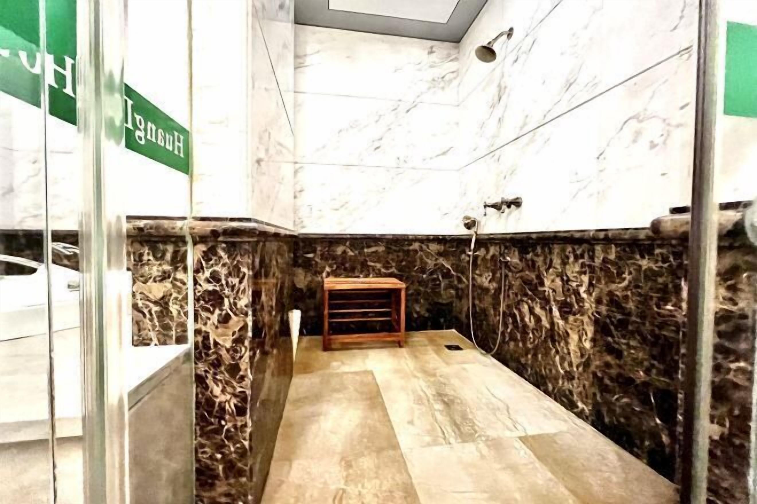 A bathroom with marble walls and a wooden bench.