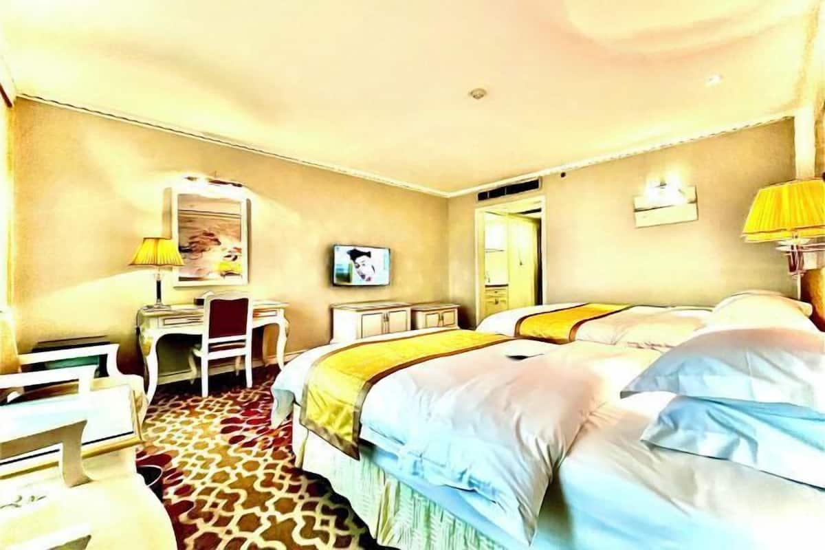A hotel room with a bed, a desk, a chair, a lamp, and a television.