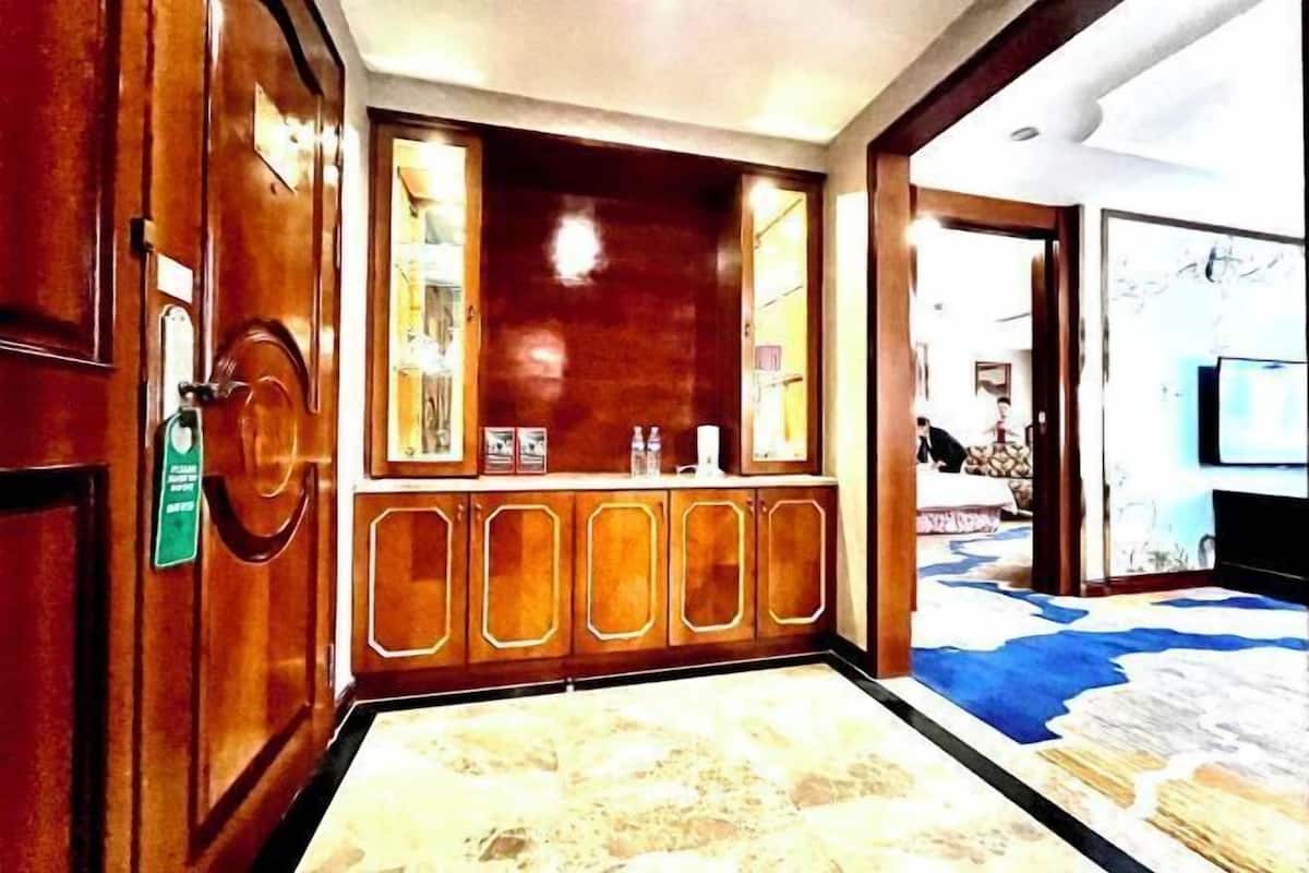 A hotel lobby with a reception desk, a large mirror, and a patterned carpet.