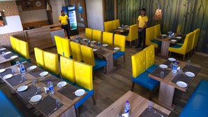 Restaurante com assentos em amarelo, mesas de madeira, um refrigerador de Pepsi e uma parede com tema de bambu.