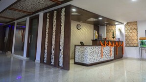 Uma área de recepção com piso de mármore, balcão de atendimento com relógio e painéis decorativos.