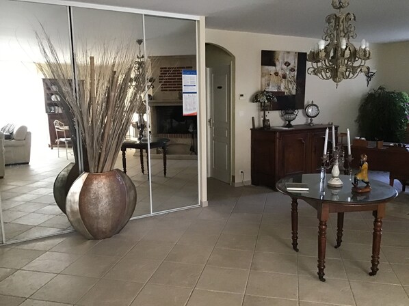 A dining area with a round table, a large mirror, and a chandelier. - Pretty house with swimming pool in Périgord (Pazayac)