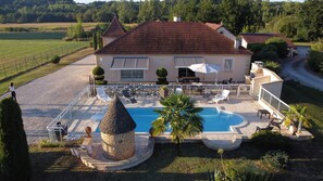 Eine Villa mit Schwimmbad, Sitzgelegenheiten im Freien und einer Steinfunktion.