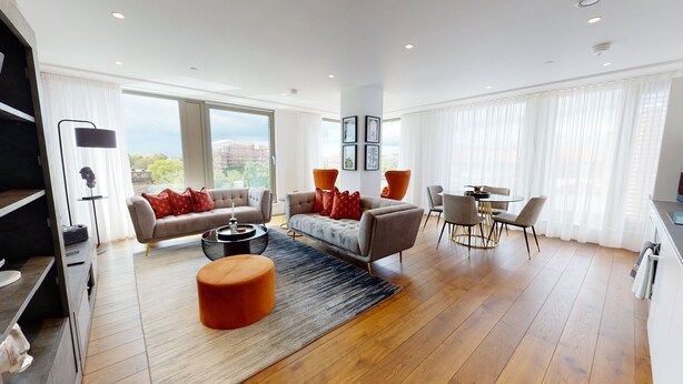 Ein modernes Wohnzimmer mit einer Couch, Hocker und Esstisch.