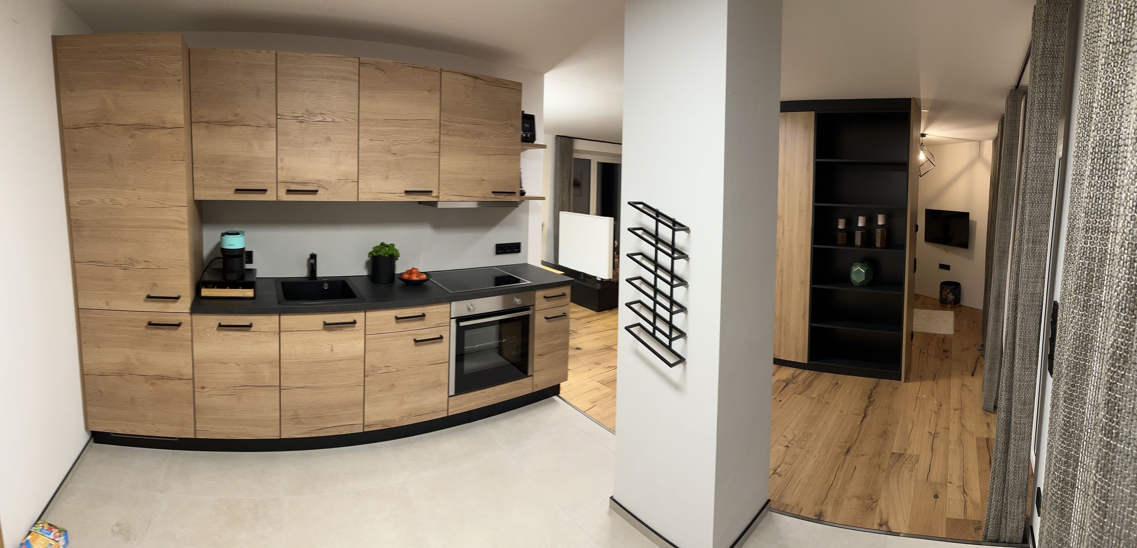 A modern kitchen with wooden cabinets, a black countertop, and a built-in oven.