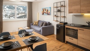 A modern apartment with a dining area, kitchen, and a sofa. - Auhof (Bad Gastein)