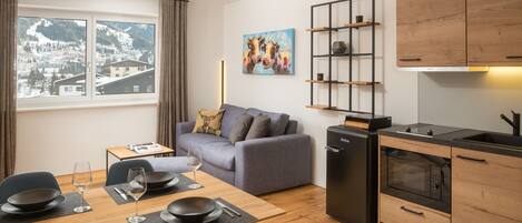 A modern apartment with a dining area, kitchen, and a sofa.