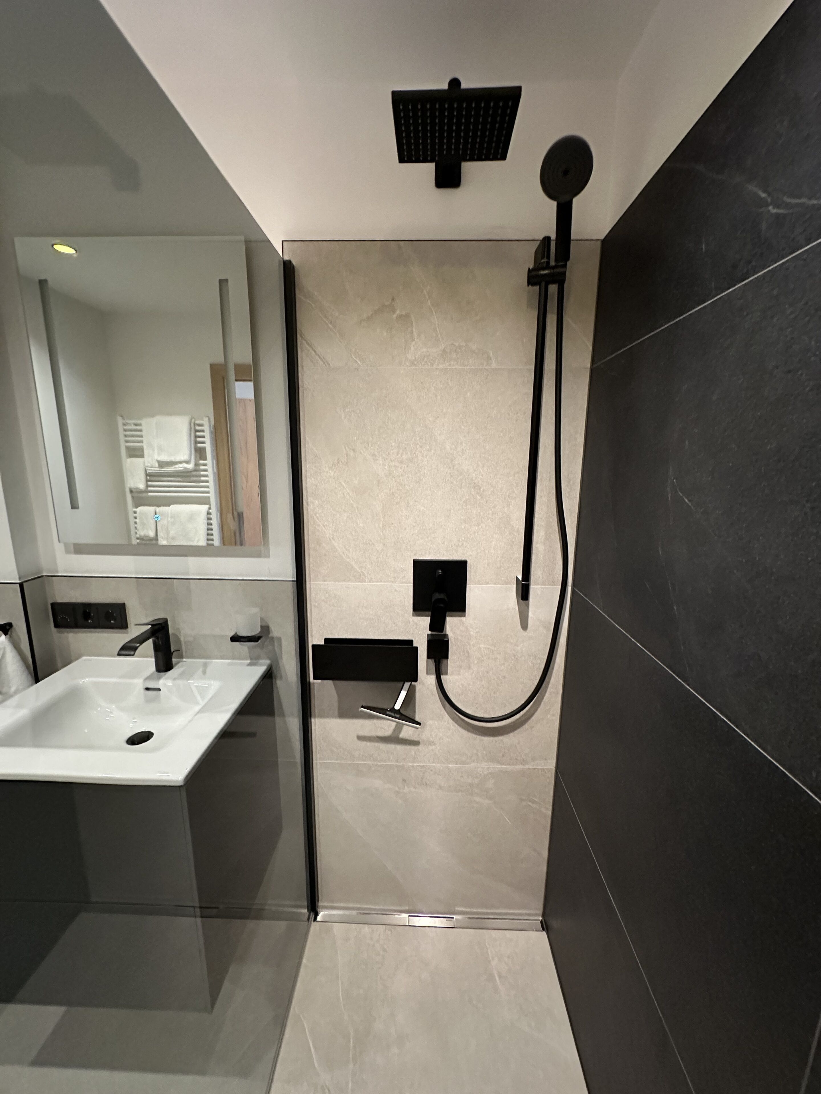 A modern bathroom with a shower, a sink, and a mirror.