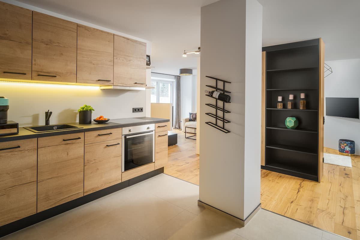 Una cocina moderna con armarios de madera, horno empotrado y un espacio para vinos.