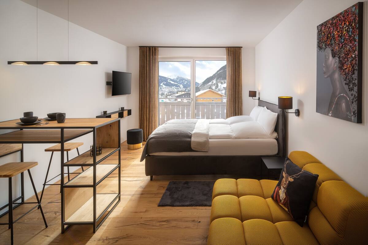 Una habitación de hotel moderna con cama, sofá, escritorio y televisión.