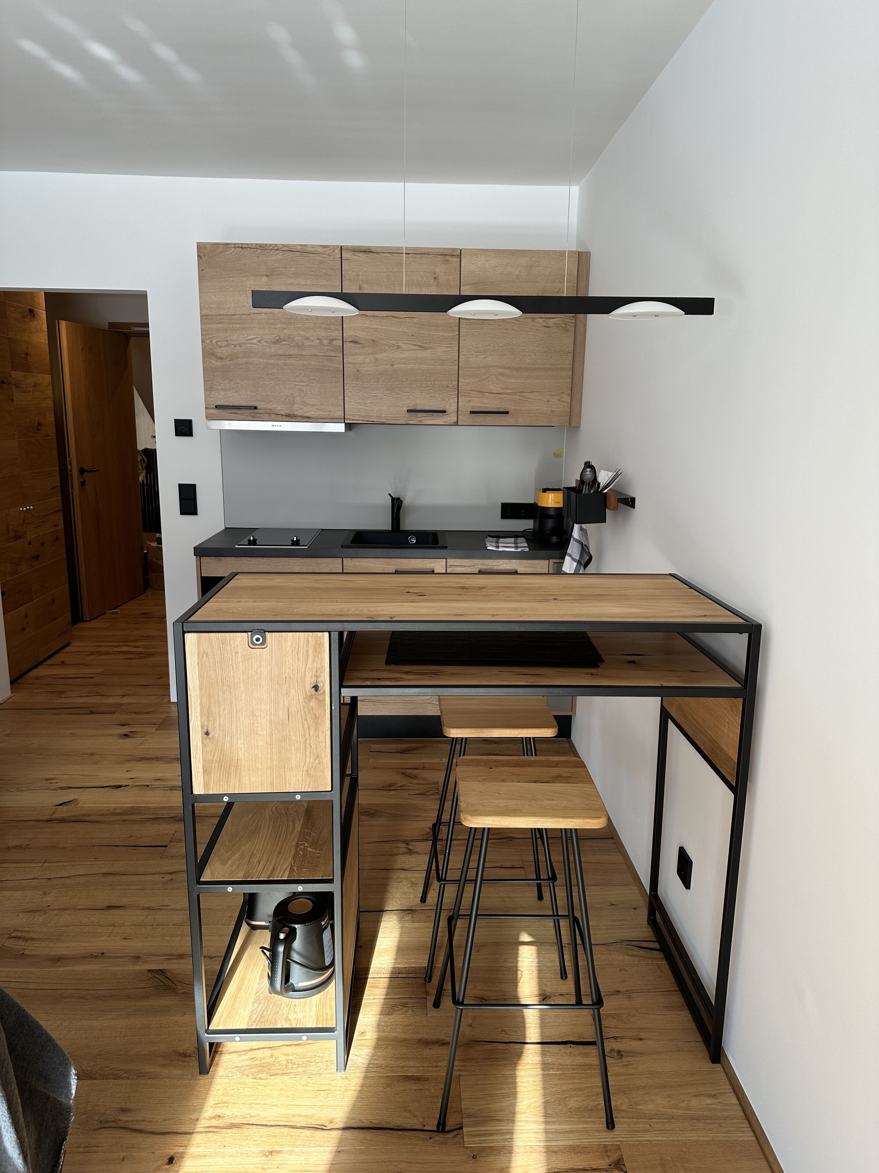 Una cucina moderna con mobili in legno, un piano di lavoro nero e un angolo caffè integrato.