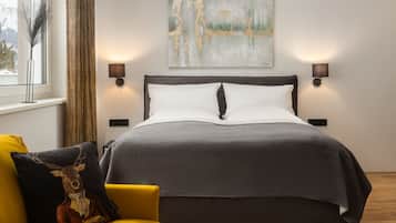 Un dormitorio moderno con una cama grande, un sofá amarillo, una mesa de centro de madera y un cuadro en la pared.