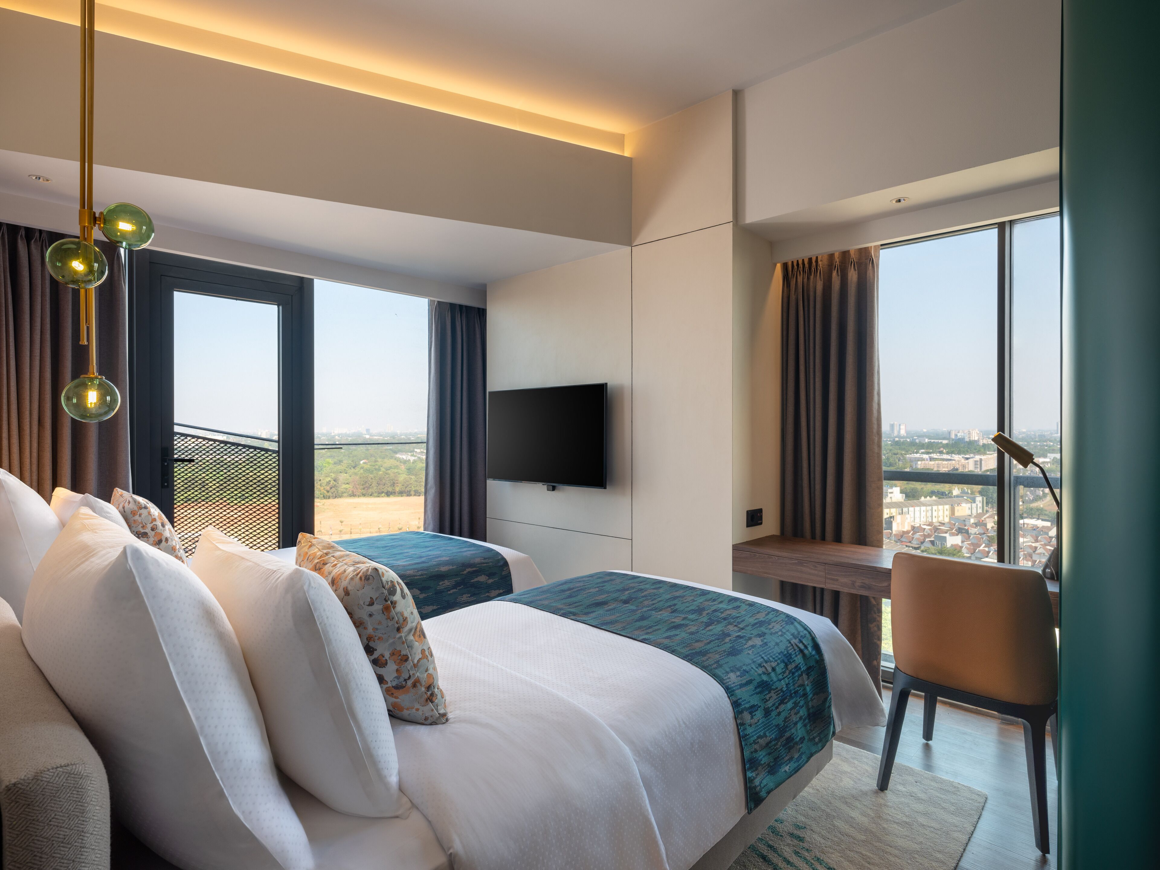 A modern hotel room with a large bed, a desk, a chair, and a TV.