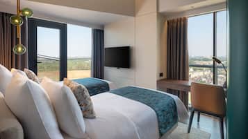 A modern hotel room with a large bed, a desk, a chair, and a TV.