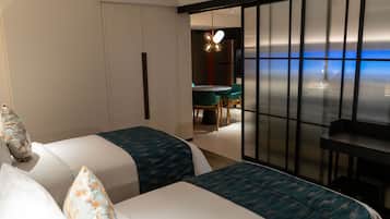 A hotel room with two beds, a desk, and a view of the sea.