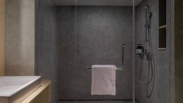 A modern bathroom with a shower, a towel rack with a towel, and a radiator.
